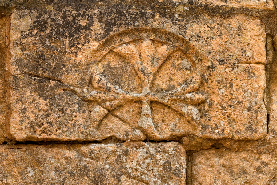 Old stone with 
lily motif in the wall of a house